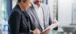 male and female businesspeople review data on a tablet