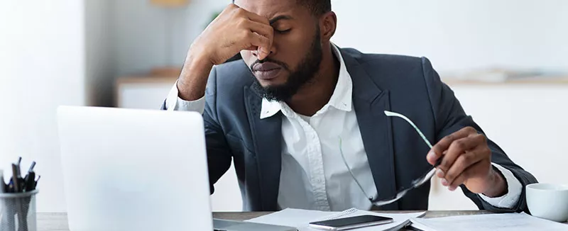 Frustrated employee pinches bridge of nose as they think