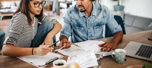 two young workers reviewing documents in front of laptop with coffee