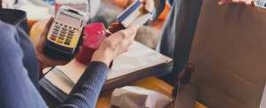 closeup of cashier handing customer credit card back while holding card reader