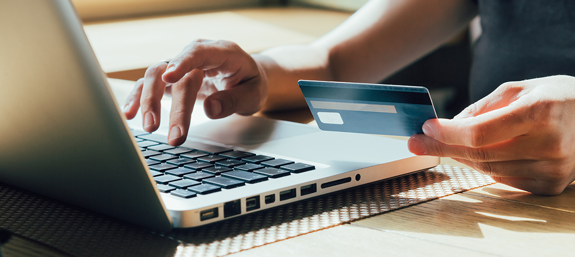 Person holding entering credit card information on a laptop